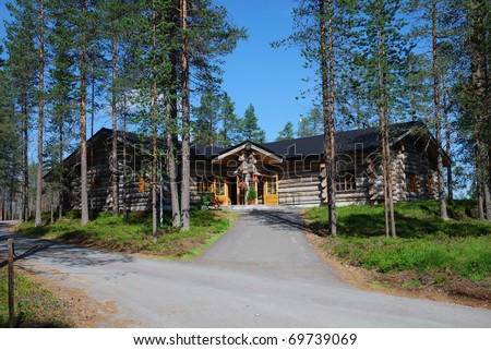 Large wooden building of restaurant is located in the middle of pine forest. It is made of big logs.