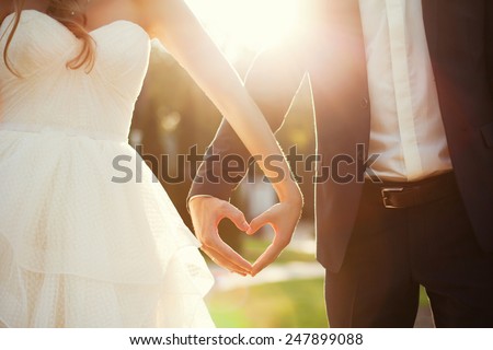 bride and groom holding hands in the shape of heart