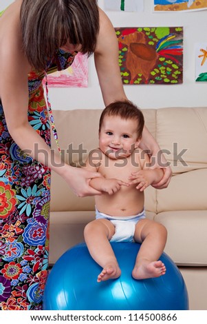 Baby gymnastic and fun with mother and large ball at home