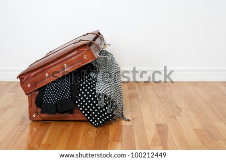 Black and white polka dot clothes in a retro leather suitcase.