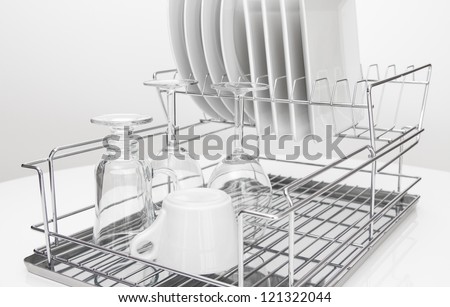 Closeup of metal dish rack with white dishes and glasses.