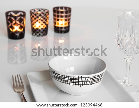 Simple table setting with three candles in glass candleholders.