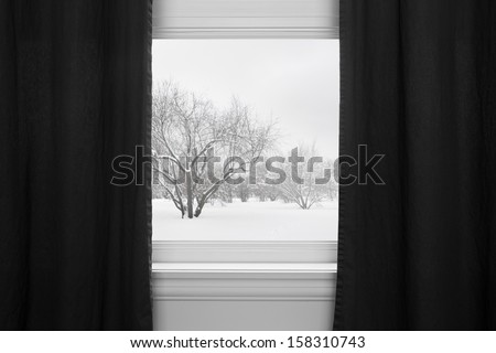 Winter landscape seen through the window with black curtains.