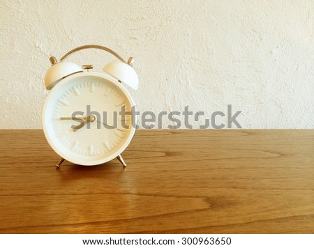 White old-fashioned alarm clock on wooden furniture.
