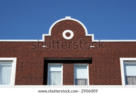 Facade and ornamental rooftop of a red brick house.