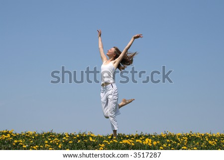 Natural beauty. Young woman in summer white clothes dancing in a flowering field.