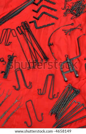 Old-fashioned wrought iron tools on red background.