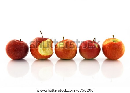 One half-bitten apple among the whole red apples, reflecting on white background.