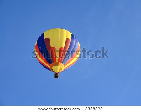 Multi colored hot air balloon up in the blue sky.