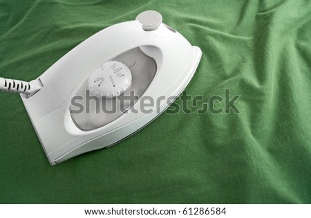 White electric iron on green cotton cloth.