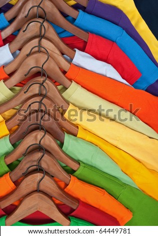 Choice of colorful casual clothes on wooden hangers.