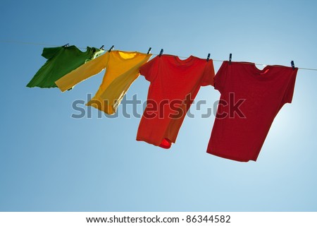 Colorful clothes hanging to dry in the blue sky, on a sunny and windy day.