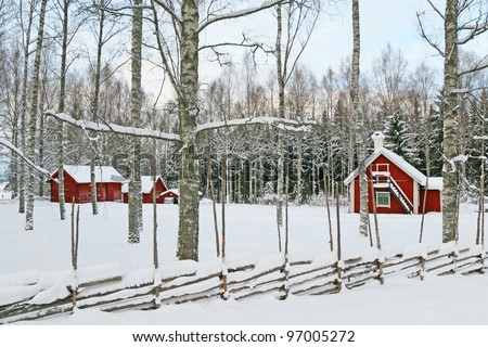 Swedish winter landscape with traditional red wooden houses covered by snow.