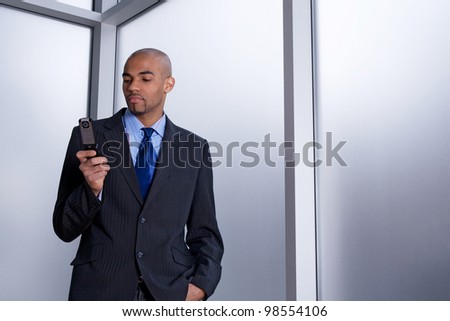Businessman beside an office window, dialing a number on his cell phone.