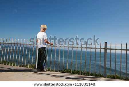 Senior man standing above the ocean looking out to ocean