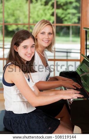 Young girl taking piano lessons from a music teacher