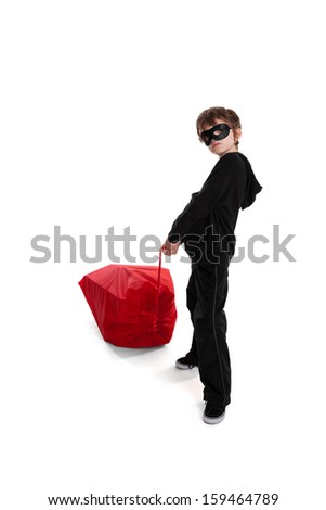 8 year old boy wearing mask stealing Santa\'s Christmas sack isolated on white background