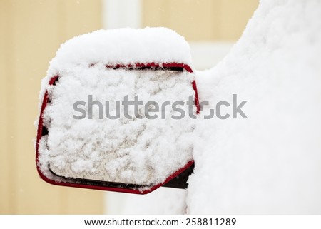 Rear view mirror of a truck covered in snow during a storm