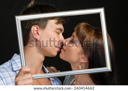 Young couple having fun making faces through tablet frame