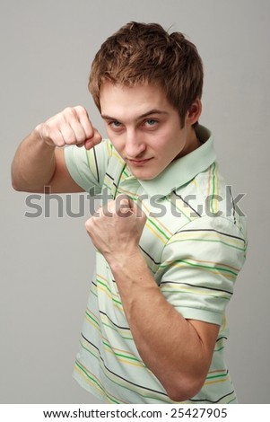 Boxing boy. The young man in standing position on a grey background.