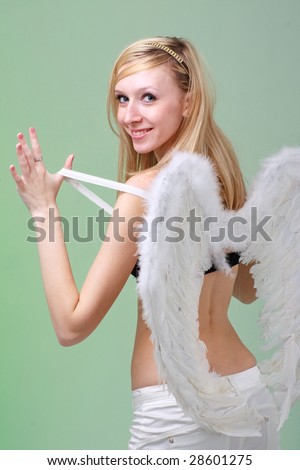 Beautiful young woman with white angel wings on a green background.