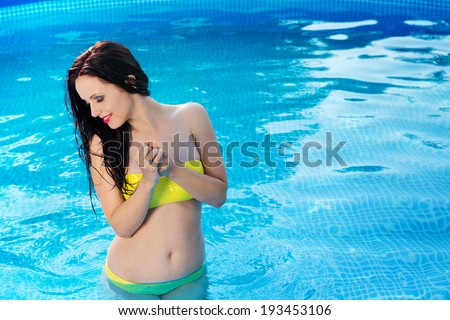 Bathing beautiful woman posing in her bikini in the swimming-poo