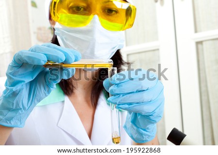 researcher mixes solutions in test tubes with yellow liquid and mixing it into a  tube full of chemical solution for an experiment in a science research lab