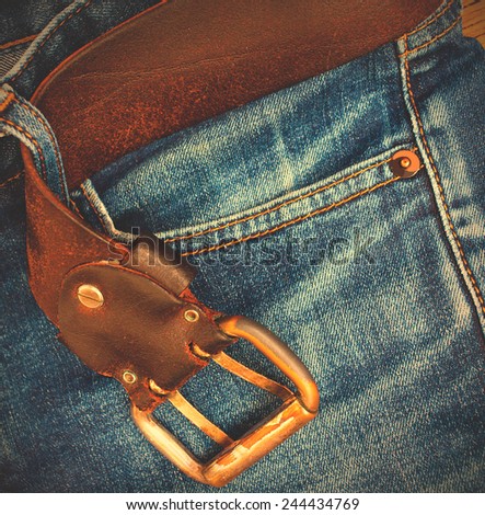 age blue jeans with a leather belt and buckle, close-up. Instagram image style