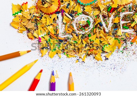 The word LOVE on the background of colored pencil shavings