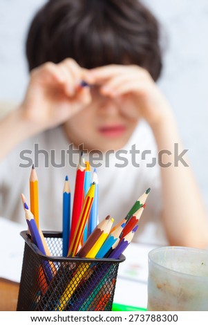 colored pencils to draw in a holder and a child on the background. focus on pencils