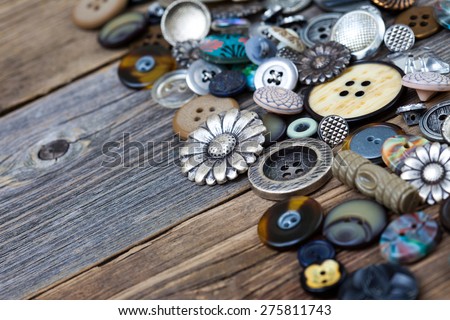 old buttons in large numbers scattered on aged wooden boards of vintage desk. Copy space
