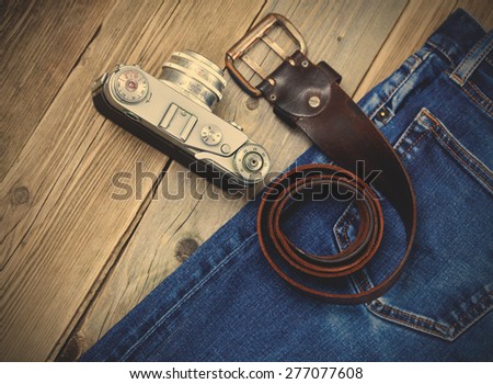 rangefinder camera, vintage leather belt and blue jeans on the old wooden boards. Kit for the traveler. instagram image filter retro style