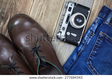 rangefinder camera, brown boots and blue jeans on the old wooden boards. Kit for the traveler