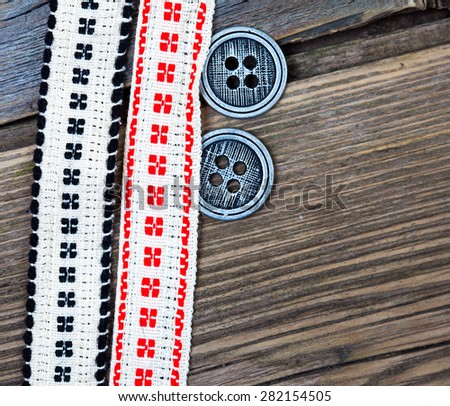 two vintage tape with embroidered ornaments andÃ?Â old buttons on a textured surface aged boards