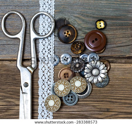 vintage buttons, tape lace and a tailor scissors on a textured surface of old boards