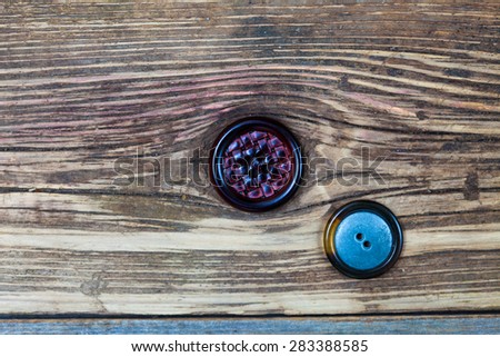 two vintage buttons on aged wood surface, close up