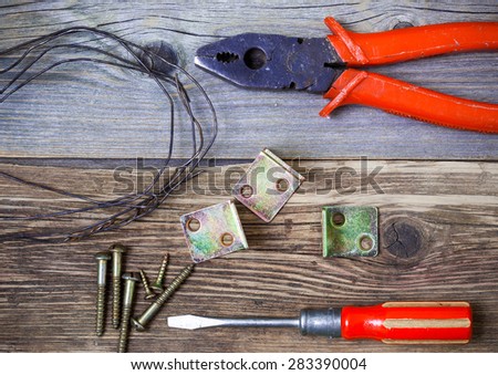 Vintage pliers and old screwdriver, screws, wire and metal corners on the boards of the aged workbench