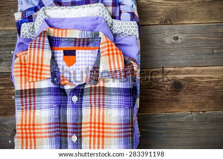 bright shirts in a pile on a wooden shelf
