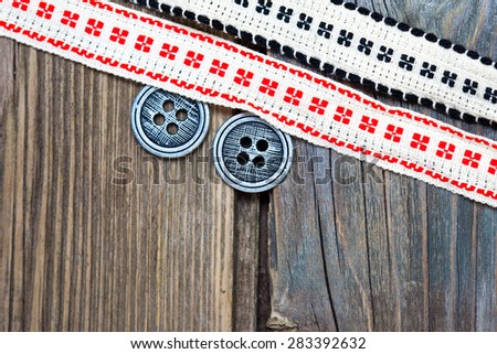 vintage ribbons with embroidered ornaments andÂ old button on a textured surface aged boards