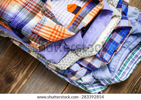bright shirts in a pile on a wooden shelf