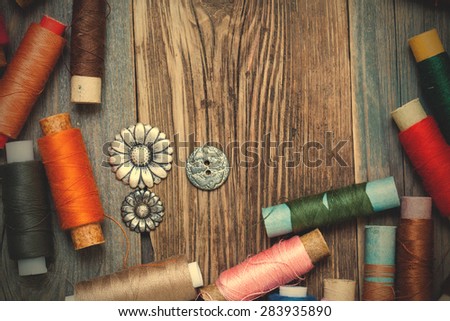 vintage tools of thread and old buttons on the textured surface of the ancient tailor\'s table with copy space. instagram image filter retro style