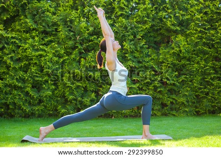 beautiful woman doing yoga on green grass in park at summer morning