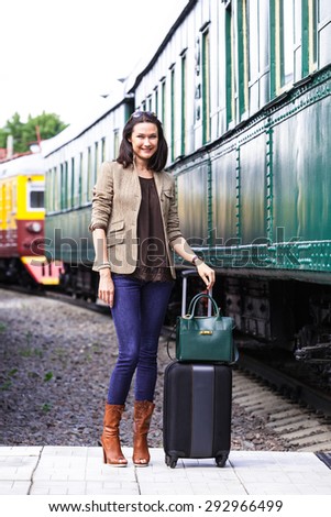 retro journey for a beautiful lady. pretty adult woman with luggage near the old railcar for travel