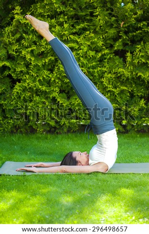 pretty woman practicing yoga in the park at summer morning on the green grass