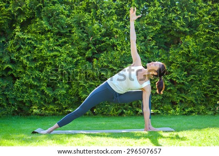 beautiful woman doing yoga on green grass in park at summer morning