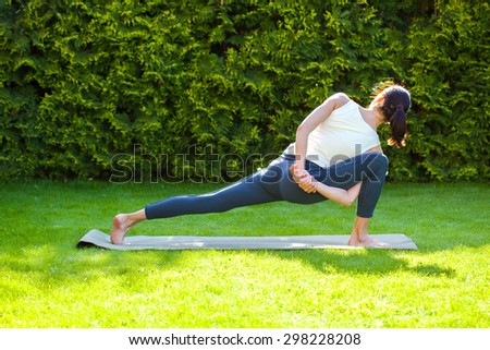 woman doing yoga on green grass in park at summer morning
