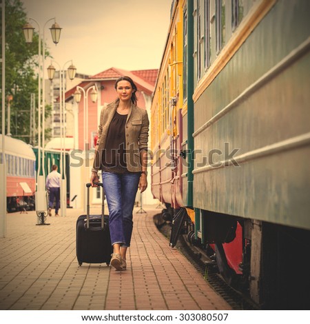 beautiful woman with luggage walking on the platform of the railway station along the train. instagram image filter retro style