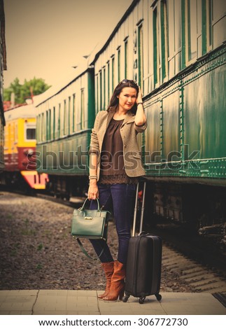 beautiful middle-aged woman with luggage near the old train. retro trip. instagram image filter retro style