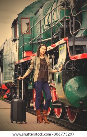 beautiful middle-aged women in retro style travel. she is near ancient train on station platform. instagram image filter retro style