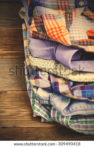 stack of bright colorful shirts on antique wooden shelf in a store. instagram image filter retro style